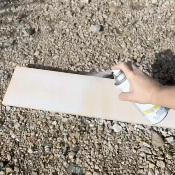 applying spray paint to wood